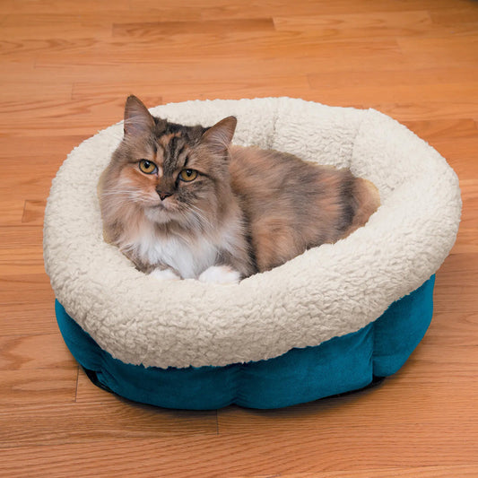 Cat sitting in a round, plush pet bed on a wooden floor