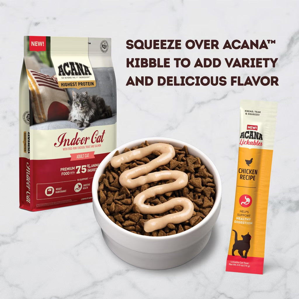 Acana cat food packaging with a bowl of cat food and a lickable treat on a marble background.