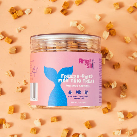 Jar of freeze-dried fish trio treats for dogs and cats on a pink background with scattered treats.
