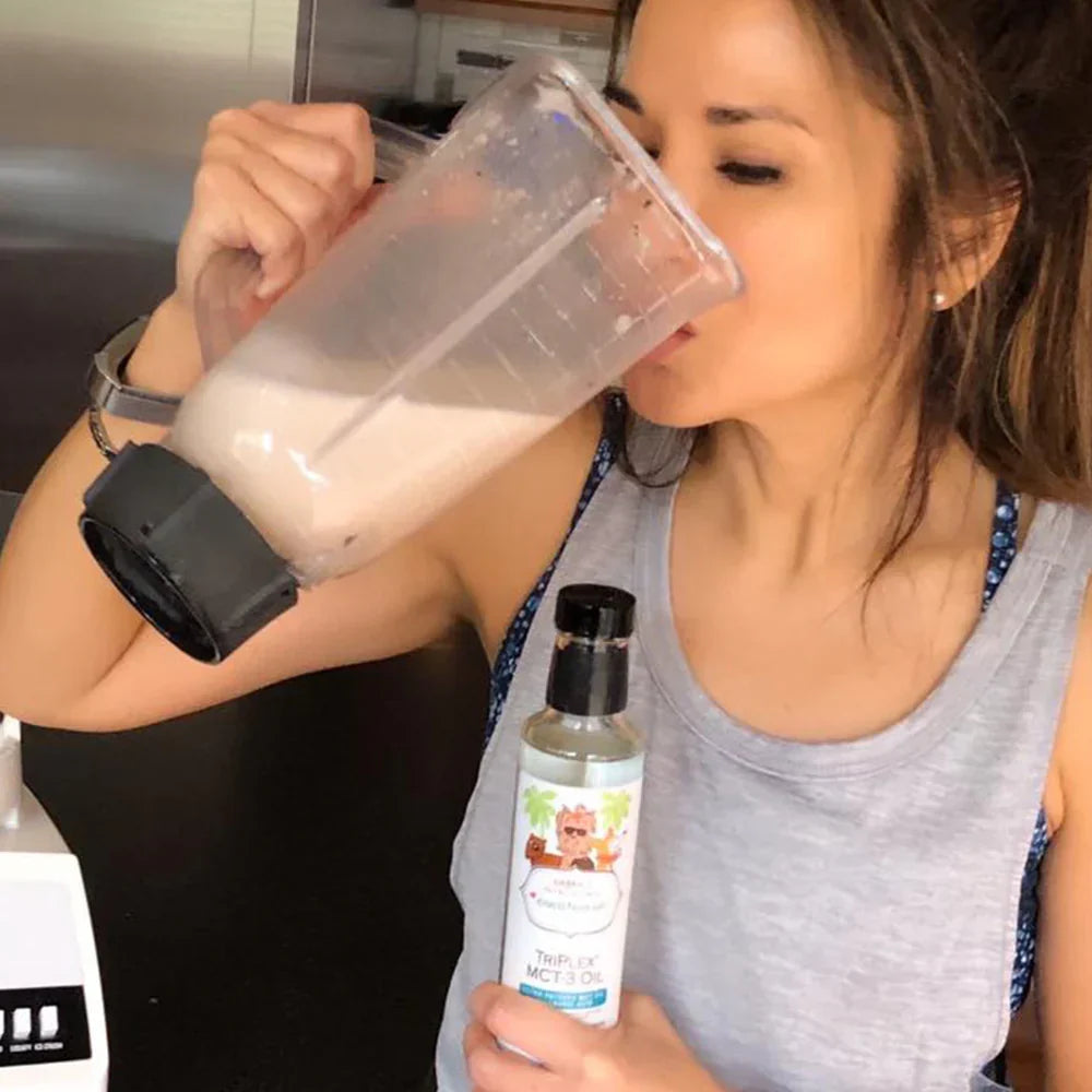 Woman holding a blender and a bottle of protein powder in a kitchen setting