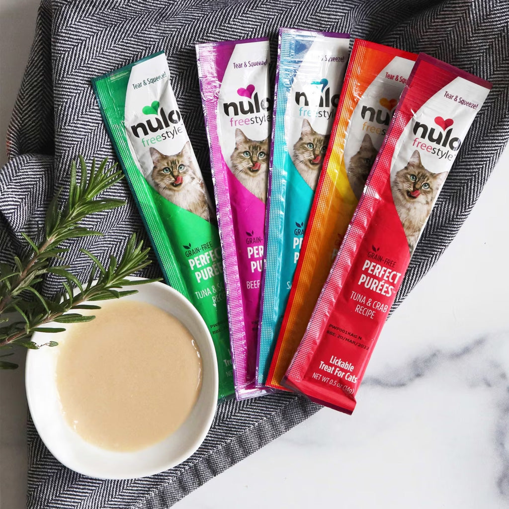 Nulo Freestyle cat food pouches with a bowl of cat food on a marble surface.