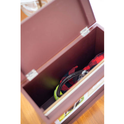 Brown wooden storage box with a tennis ball and red object inside, on a wooden floor.
