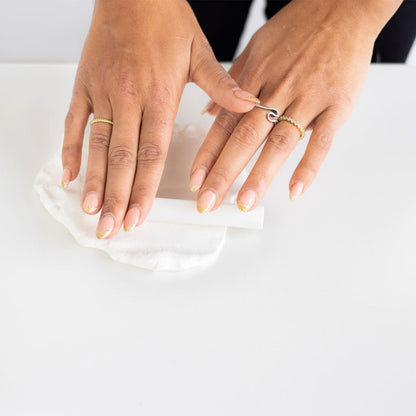 Hands with gold rings on a white surface